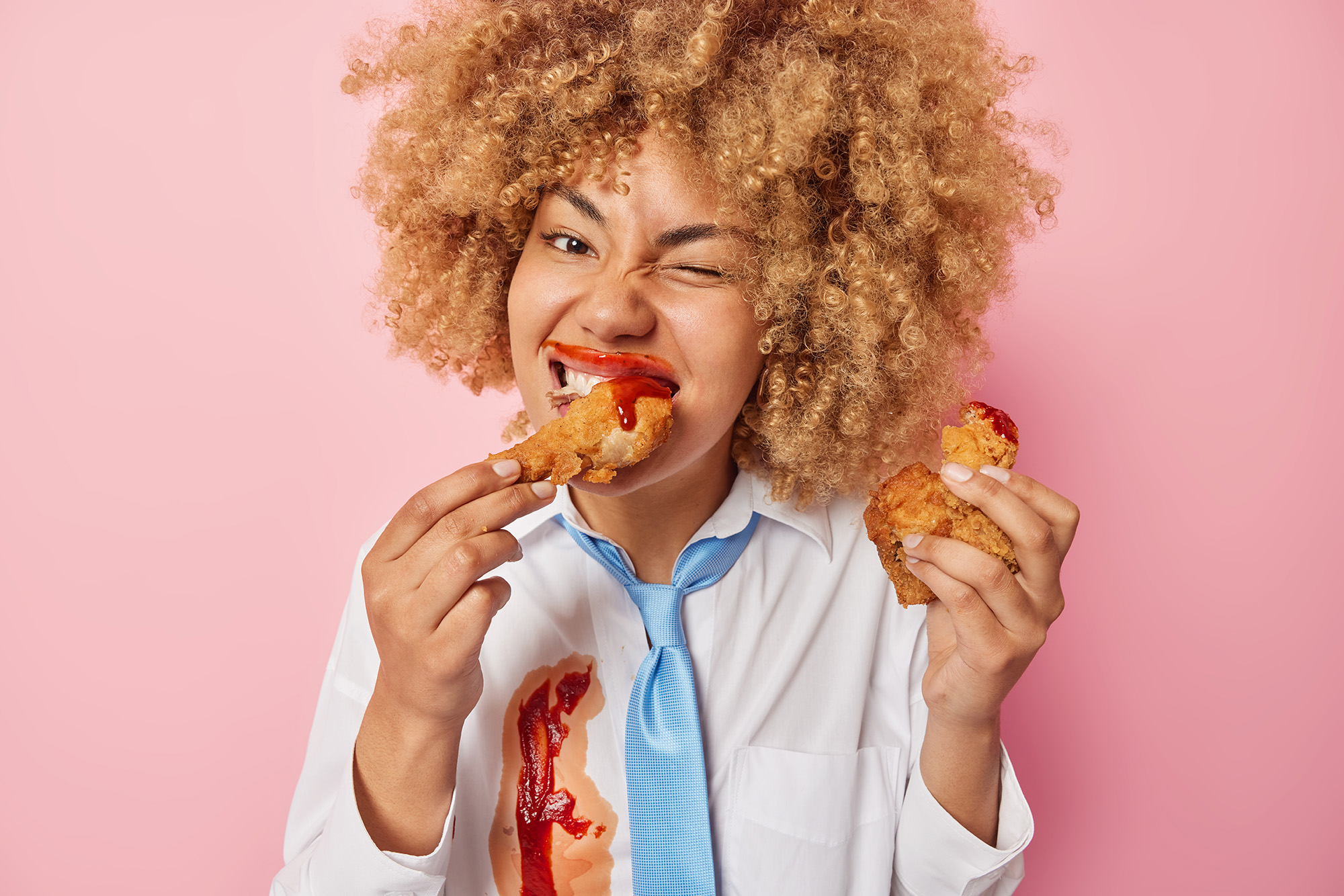 Cheerful Curly Haired Woman Eats Delicious Meal Fast Food Smeared With Ketchup Keeps Unhealthy Nutrition Has Binge Eating Habit Wears White Shirt Blue Tie Isolated Pink Background Copy Copy